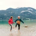 Older couple holding hands in water with mountains in background